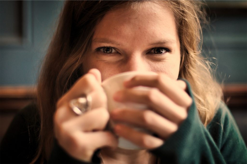 Woman holds a mug of tea close to her face. Tea brings single mom joy!